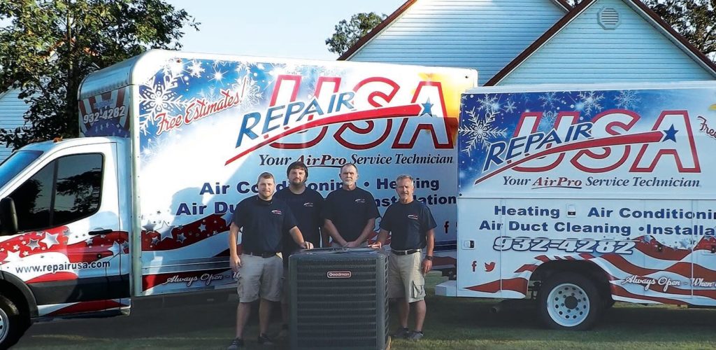 RepairUSA team members standing around a central air conditioner units with branded trucks in the background.