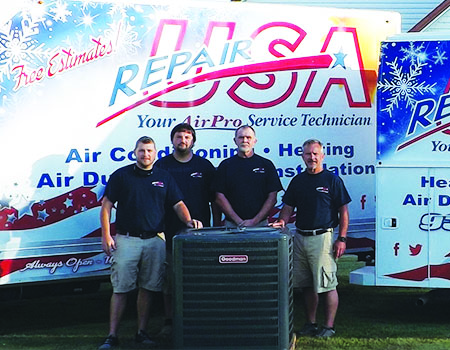 Four RepairUSA team members posing behind an HVAC unit.